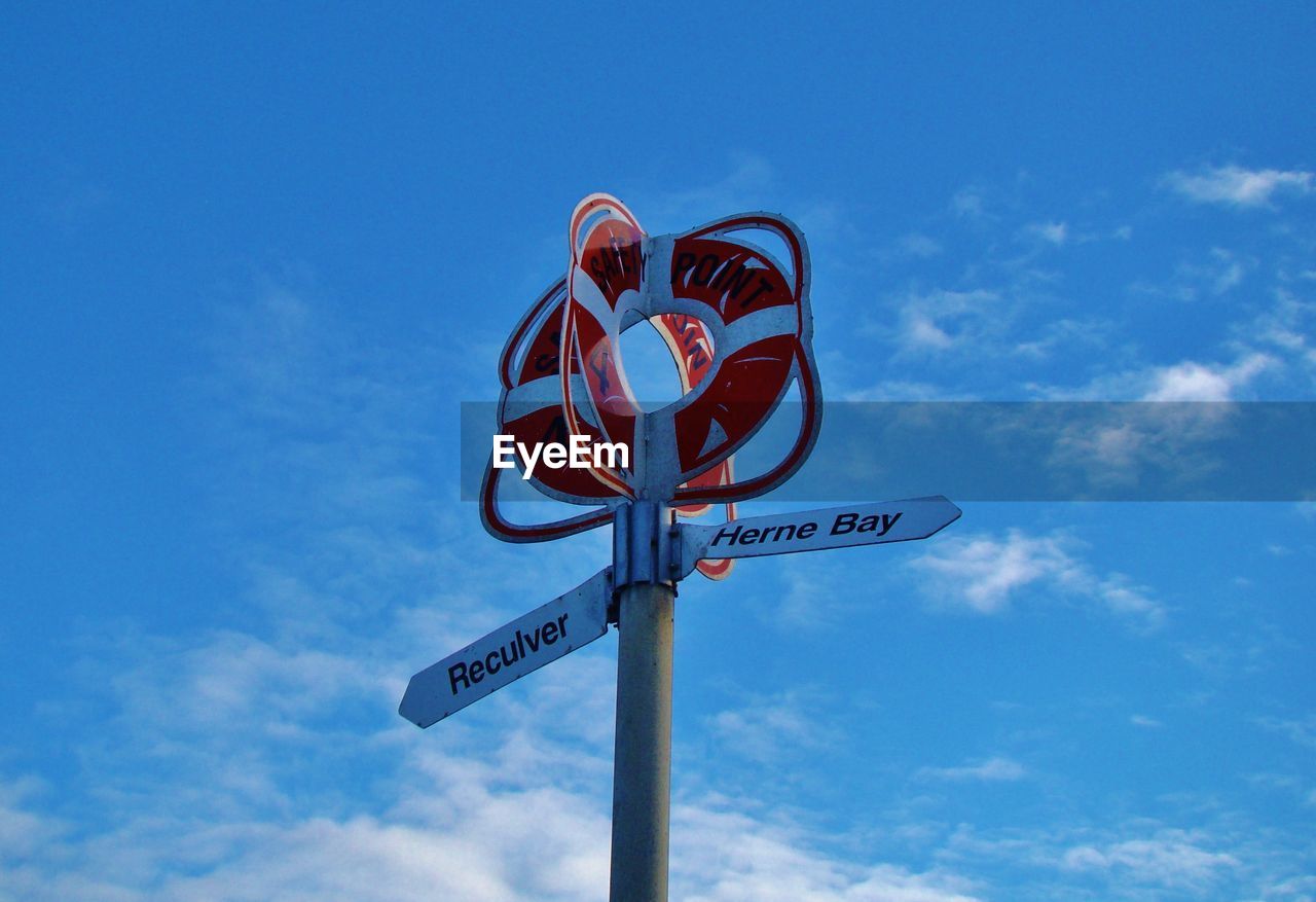 Low angle view of road sign against blue sky