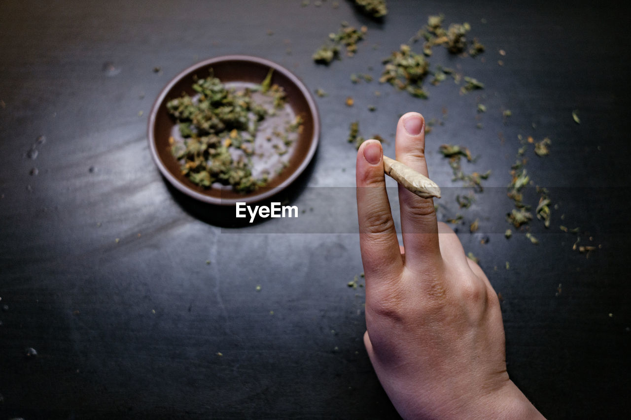 Cropped hands of man holding marijuana joint