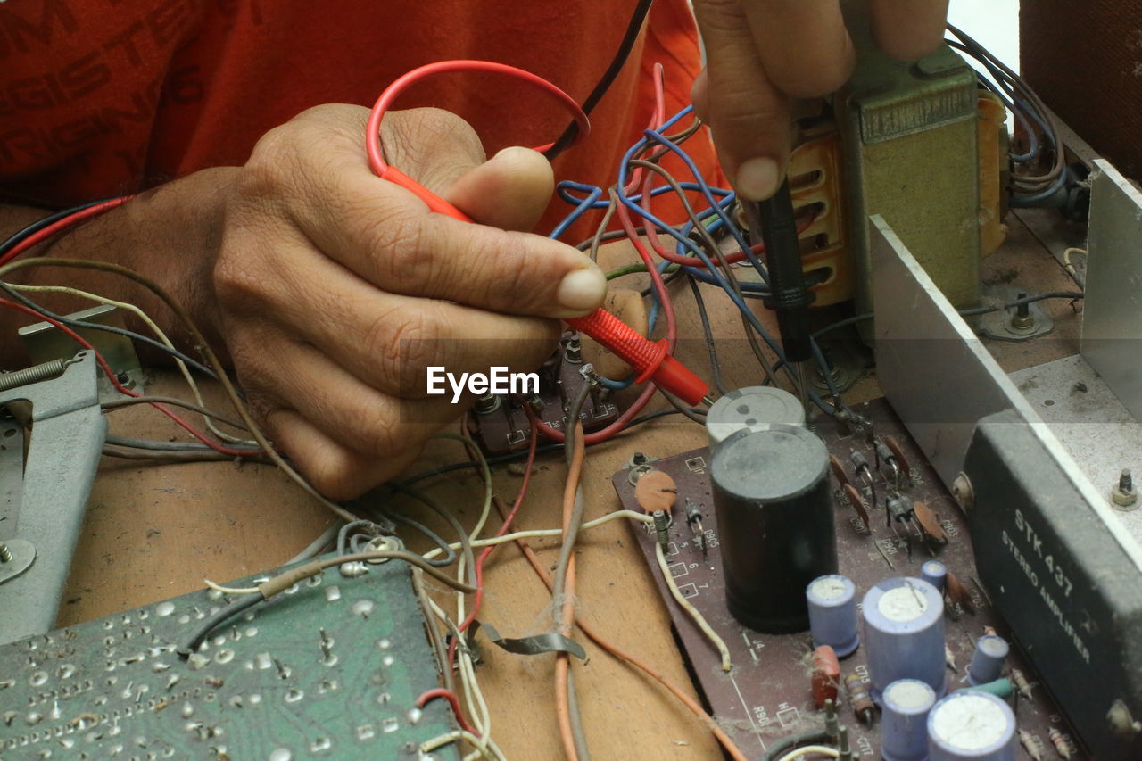 Cropped hands of male technician repairing radio