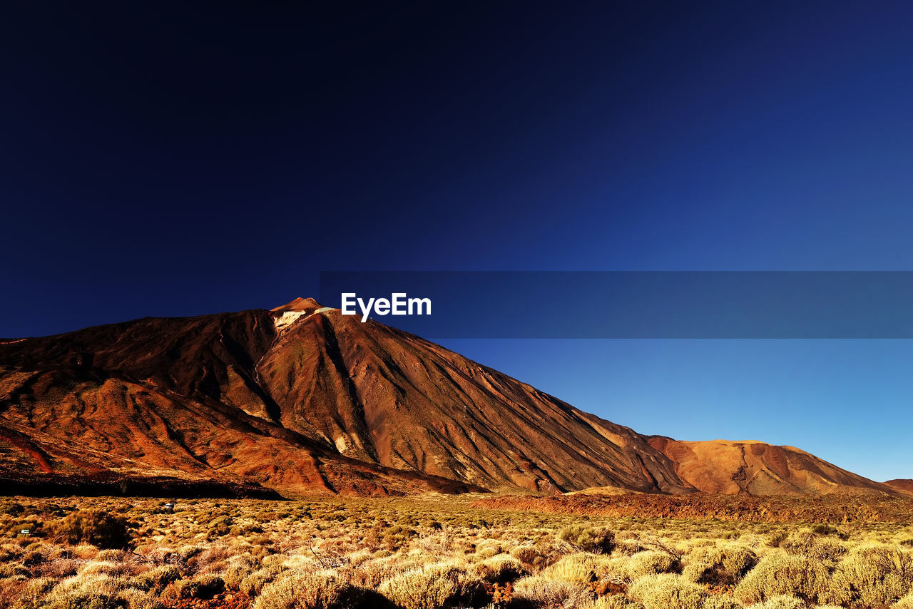 Scenic view of rocky mountain at el teide national park against clear blue sky