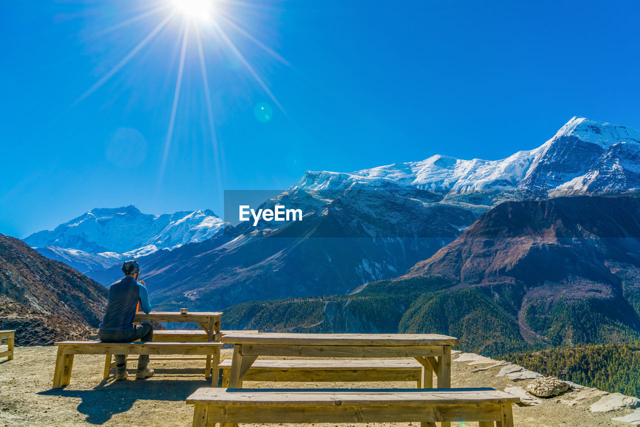 Man sitting on bench by mountains
