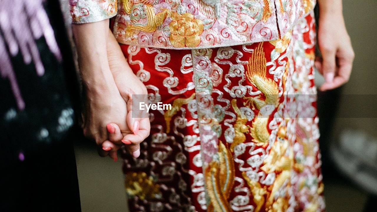 Midsection of women wearing traditional clothes while holding hands