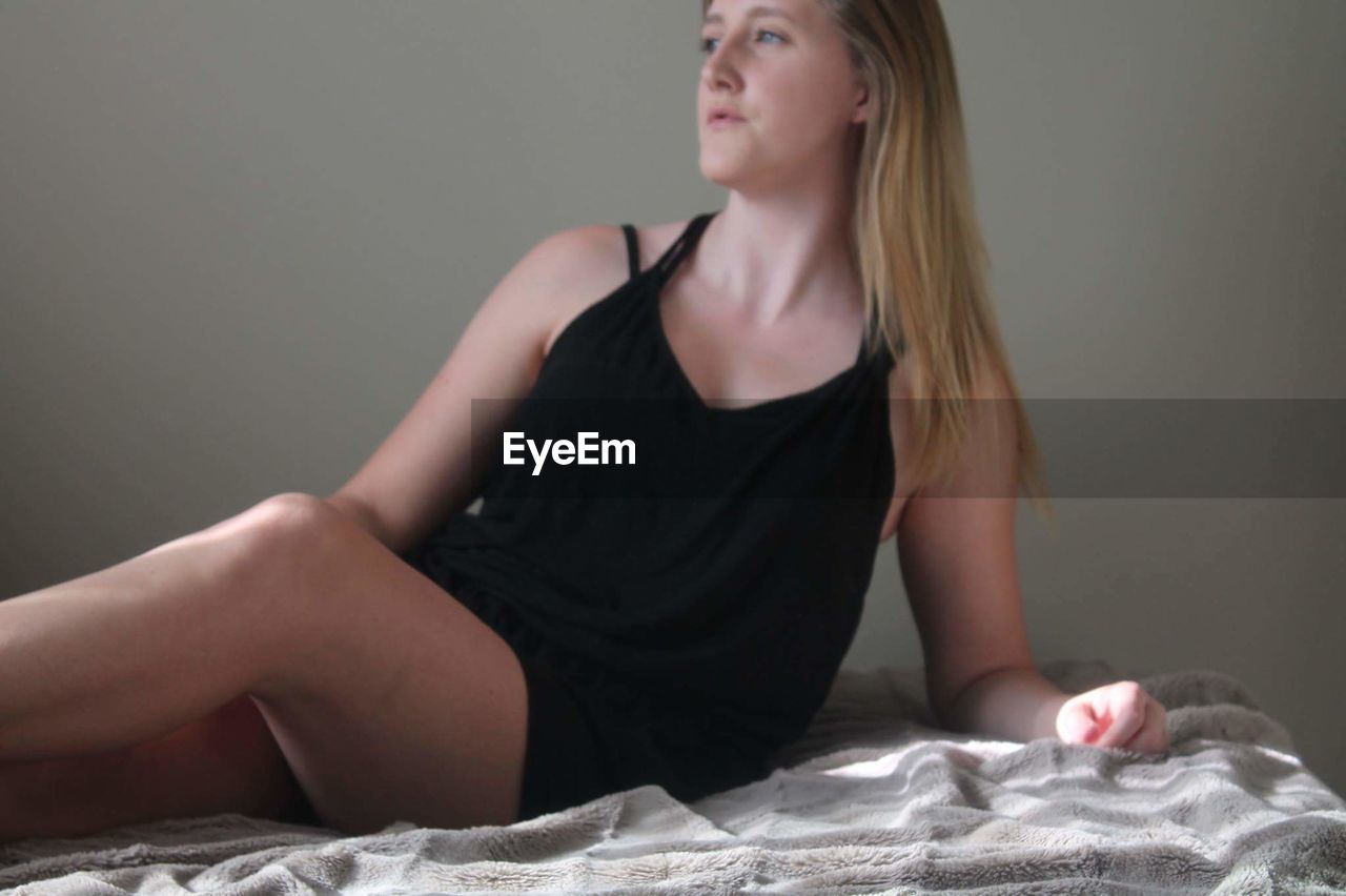 Woman looking away while reclining on bed at home