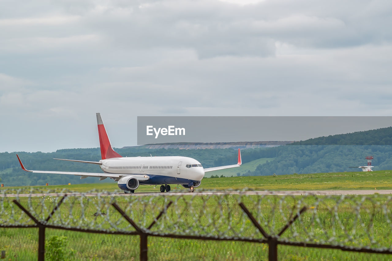 A civilian passenger plane with turbojet engines accelerates along the runway on the airport field