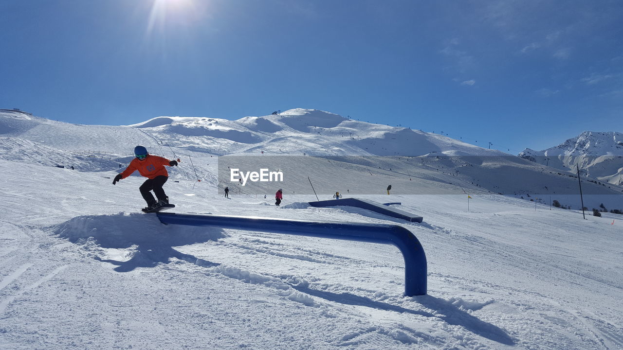 PERSON SKIING ON SNOWCAPPED MOUNTAIN AGAINST SKY