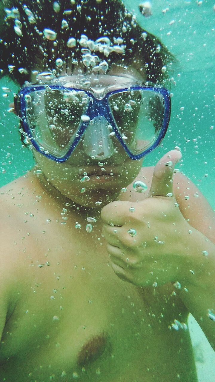 Shirtless man showing thumbs up in swimming pool