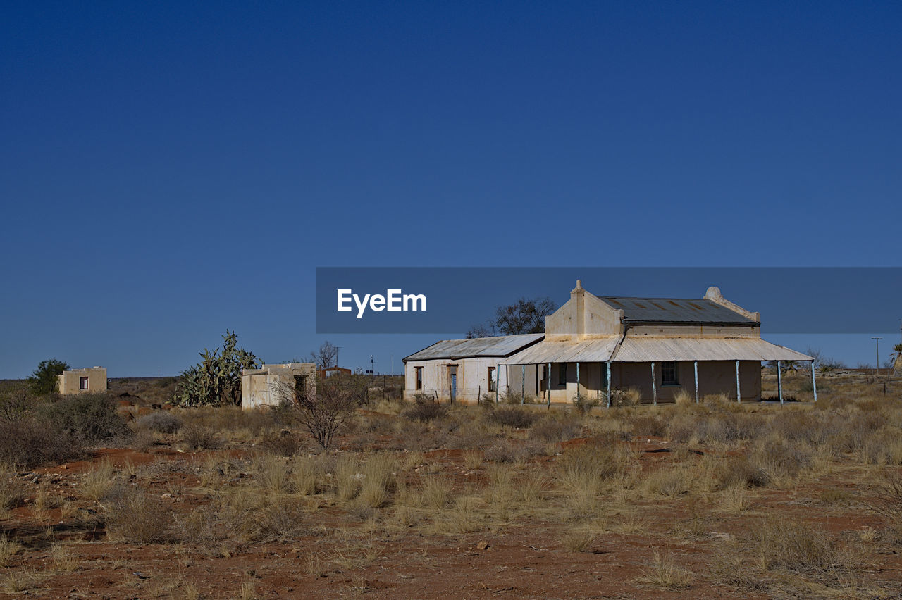 HOUSE ON FIELD AGAINST CLEAR SKY