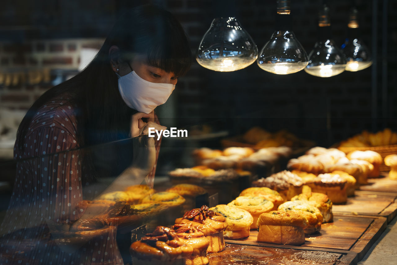 Young woman wearing mask looking at food at store