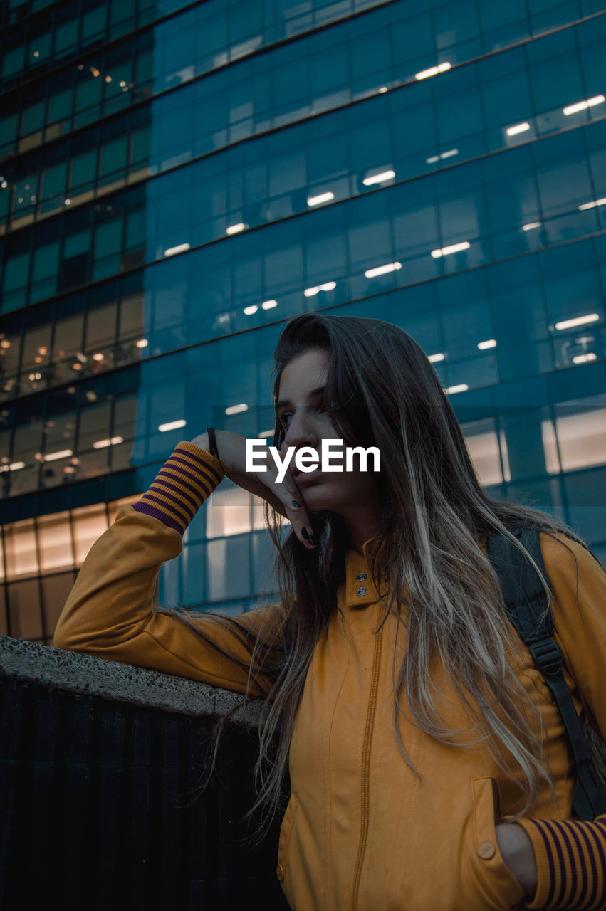 BEAUTIFUL YOUNG WOMAN LOOKING AT CITY IN OFFICE