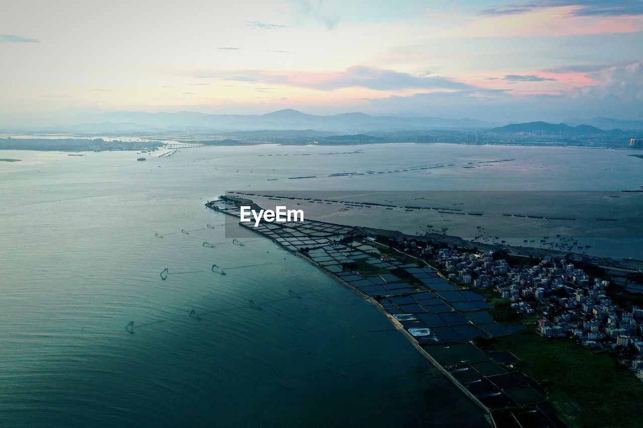 HIGH ANGLE VIEW OF SHORE BY SEA AGAINST SKY