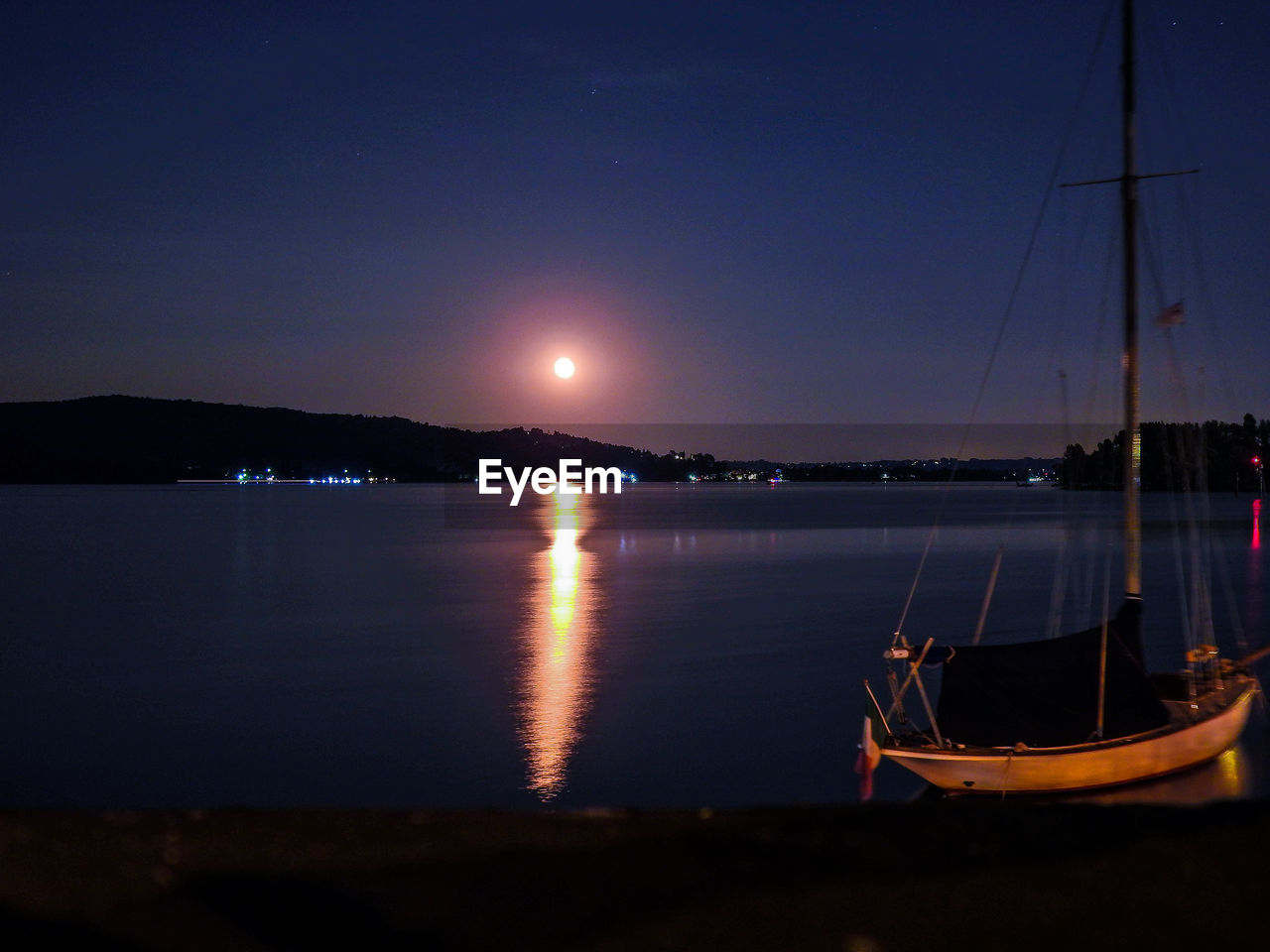 SAILBOATS MOORED IN SEA AT NIGHT