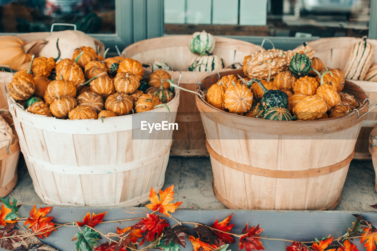 Red, yellow, green pumpkins in baskets by store on farm. store outdoor decoration.