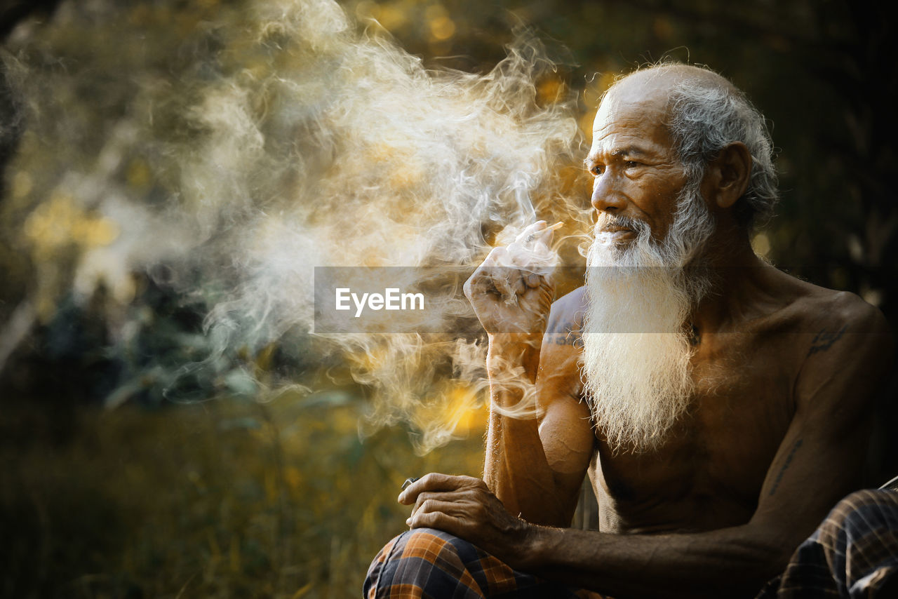 Senior man smoking while sitting outdoors