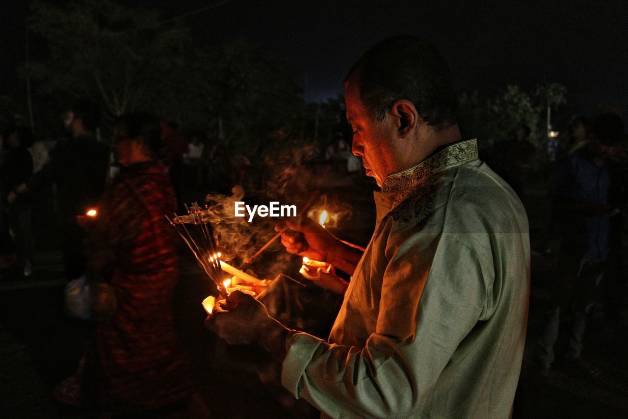 Man holding dia, oil-lamp at rakher upobash barodi lokhnath brahmachari ashram in night time 