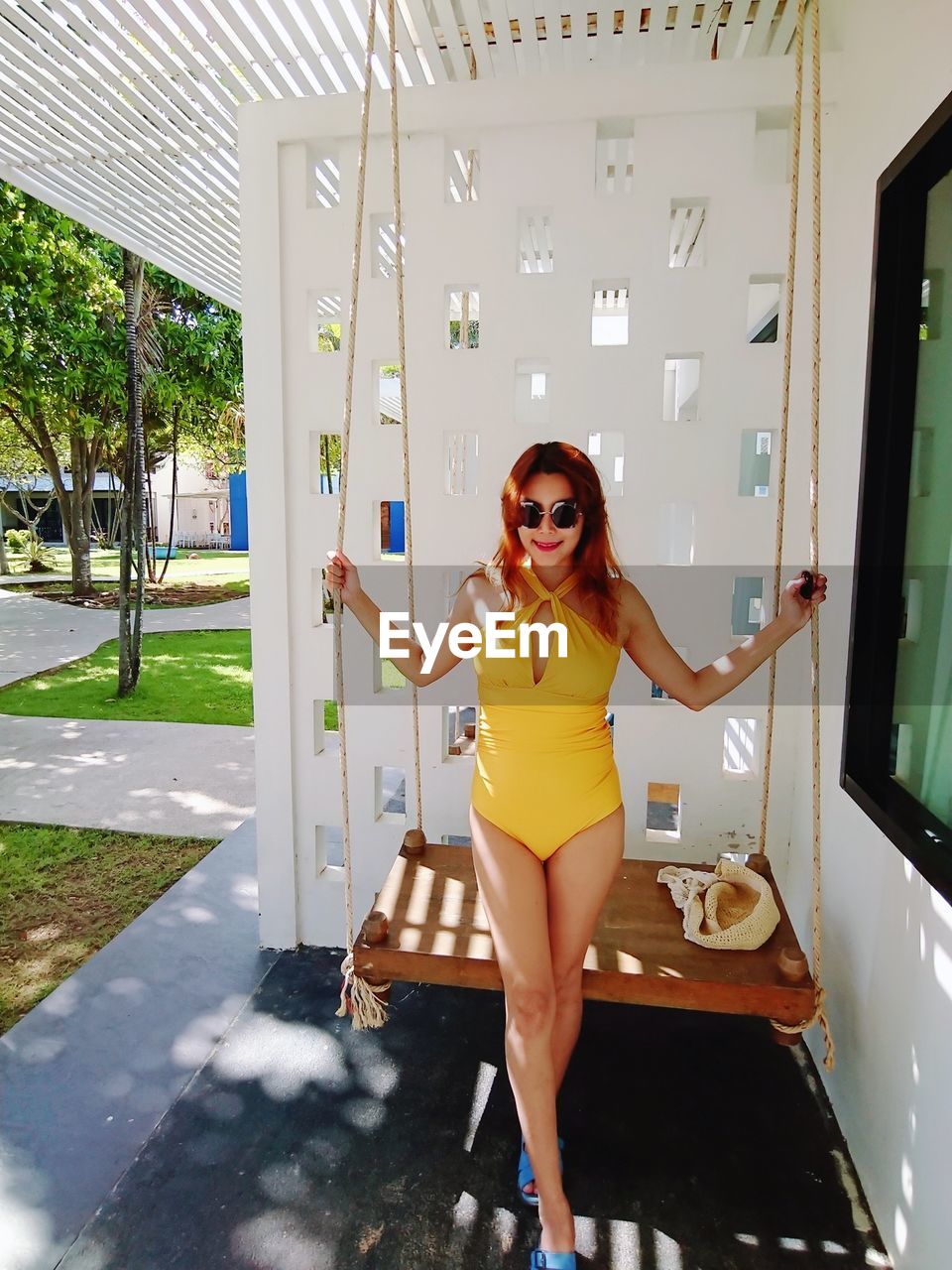 Portrait of woman standing by swing outdoors