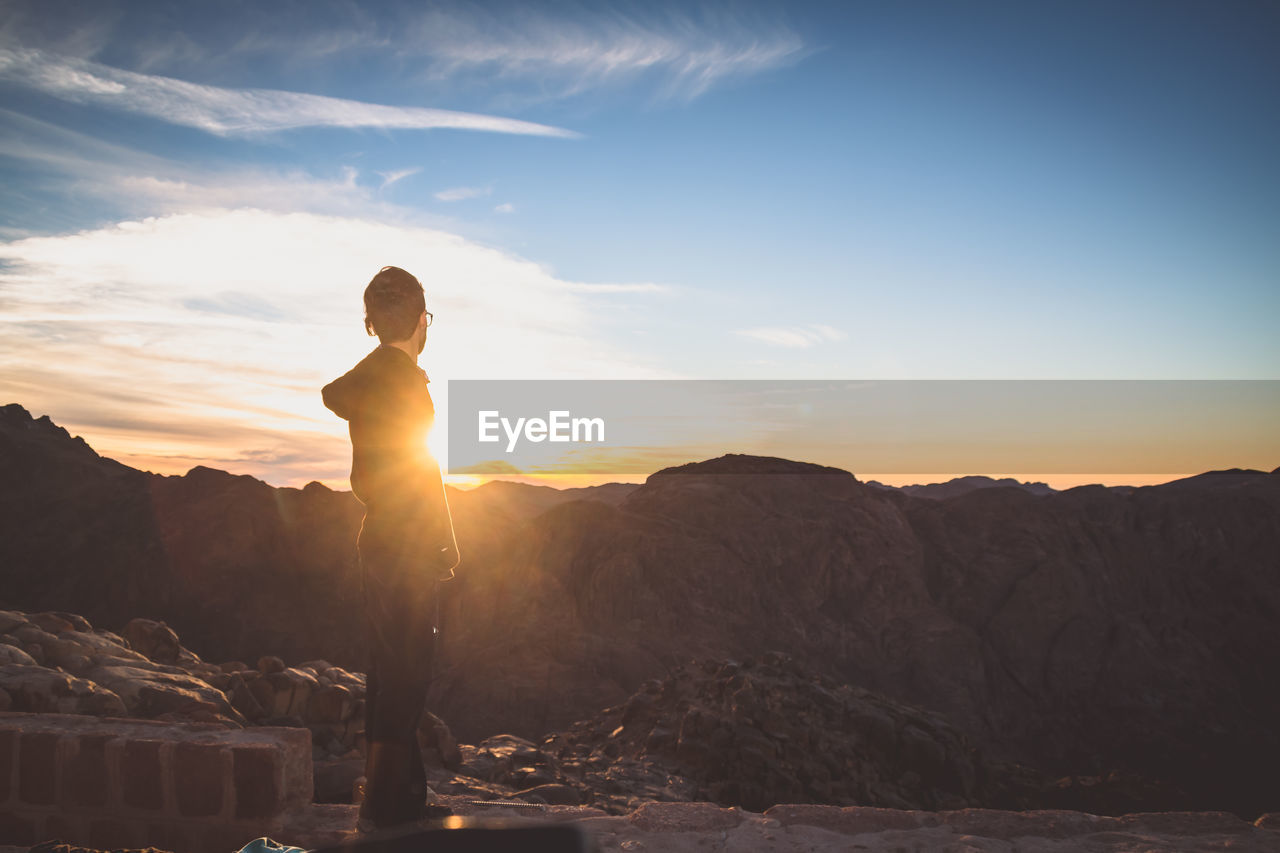 Side view of man standing on mountain during sunset