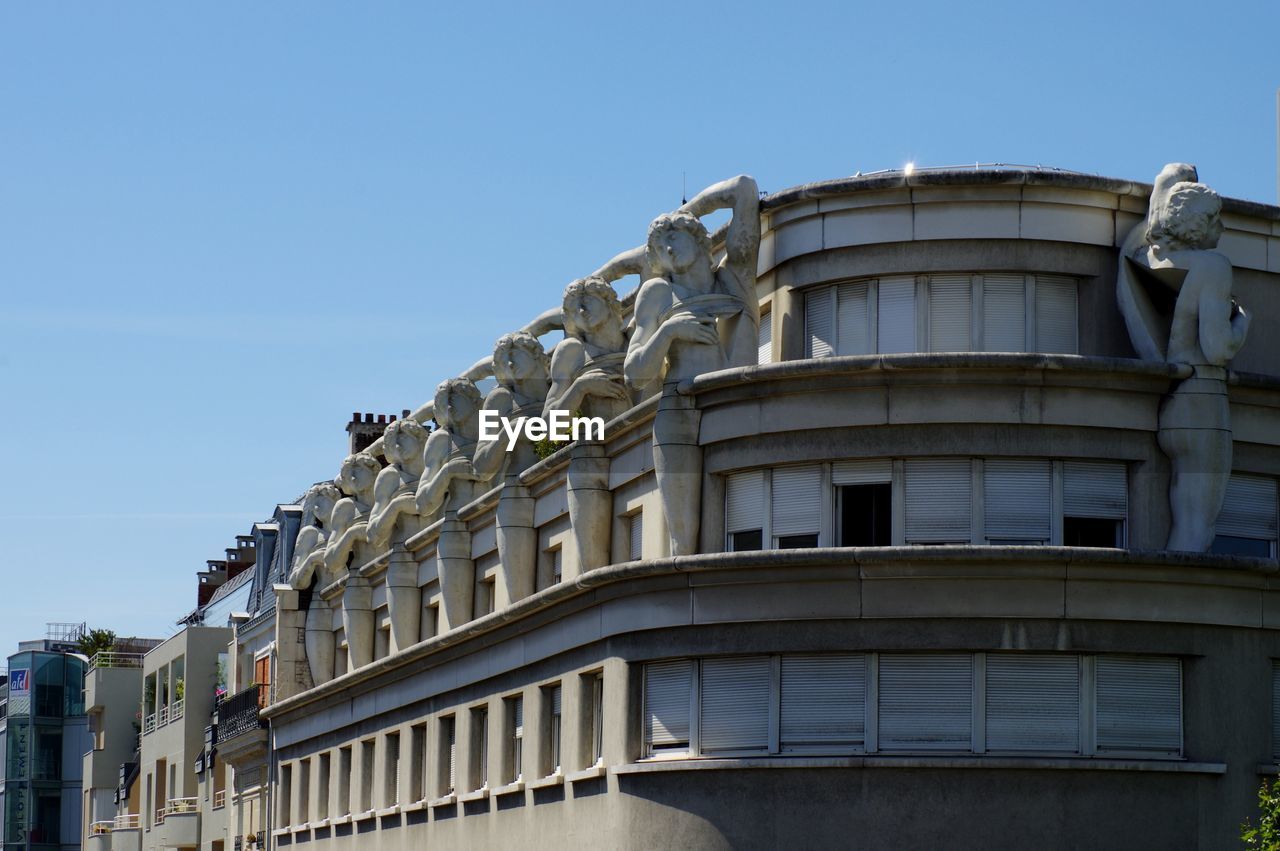 Sculptures on building against clear sky in city