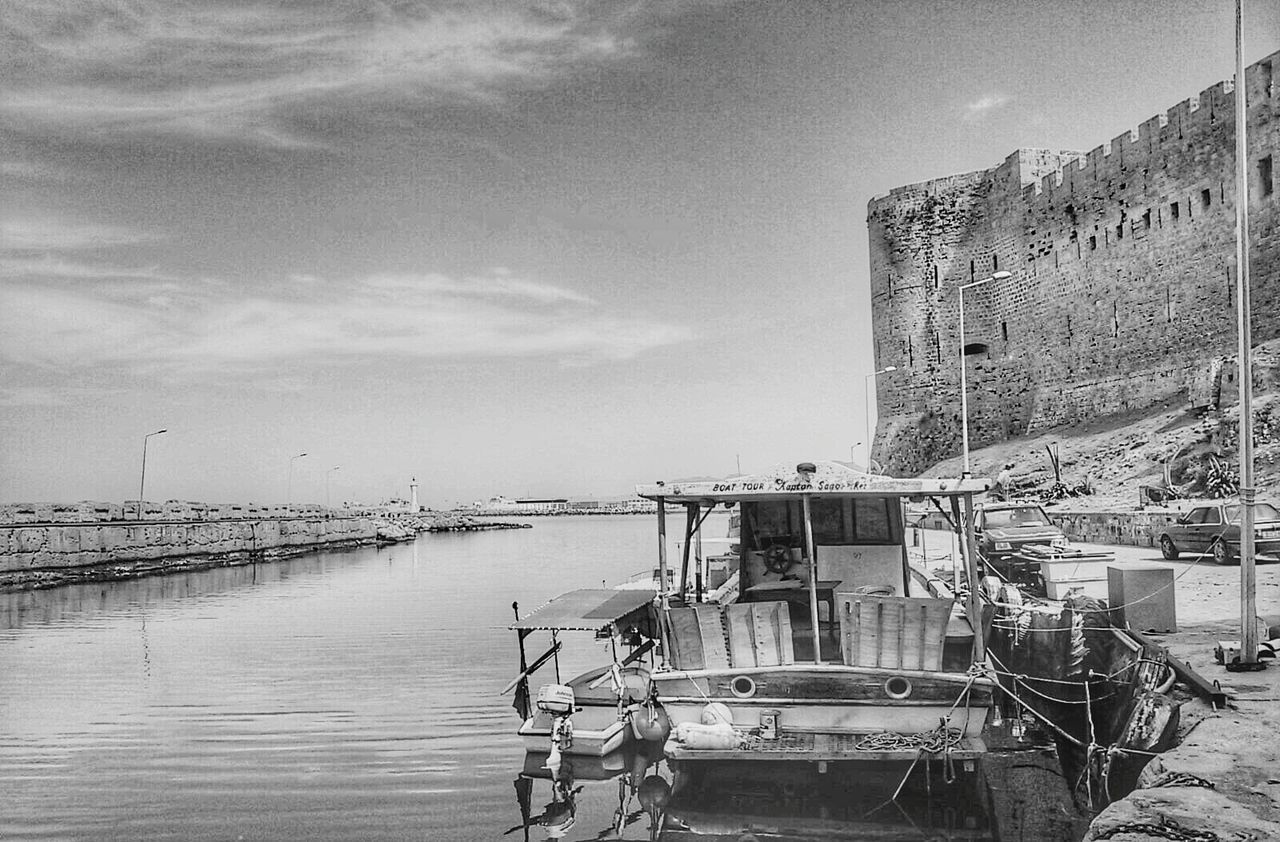Boat moored at harbor by kyrenia castle against sky