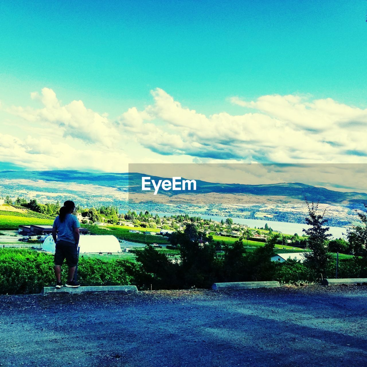 REAR VIEW OF WOMAN STANDING ON LANDSCAPE