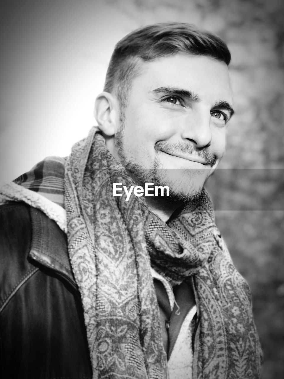 Close-up of smiling young man looking away against sky