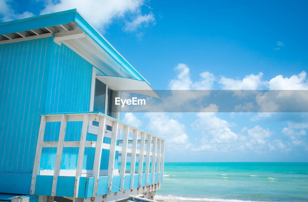 Blue lifeguard hut by sea against sky