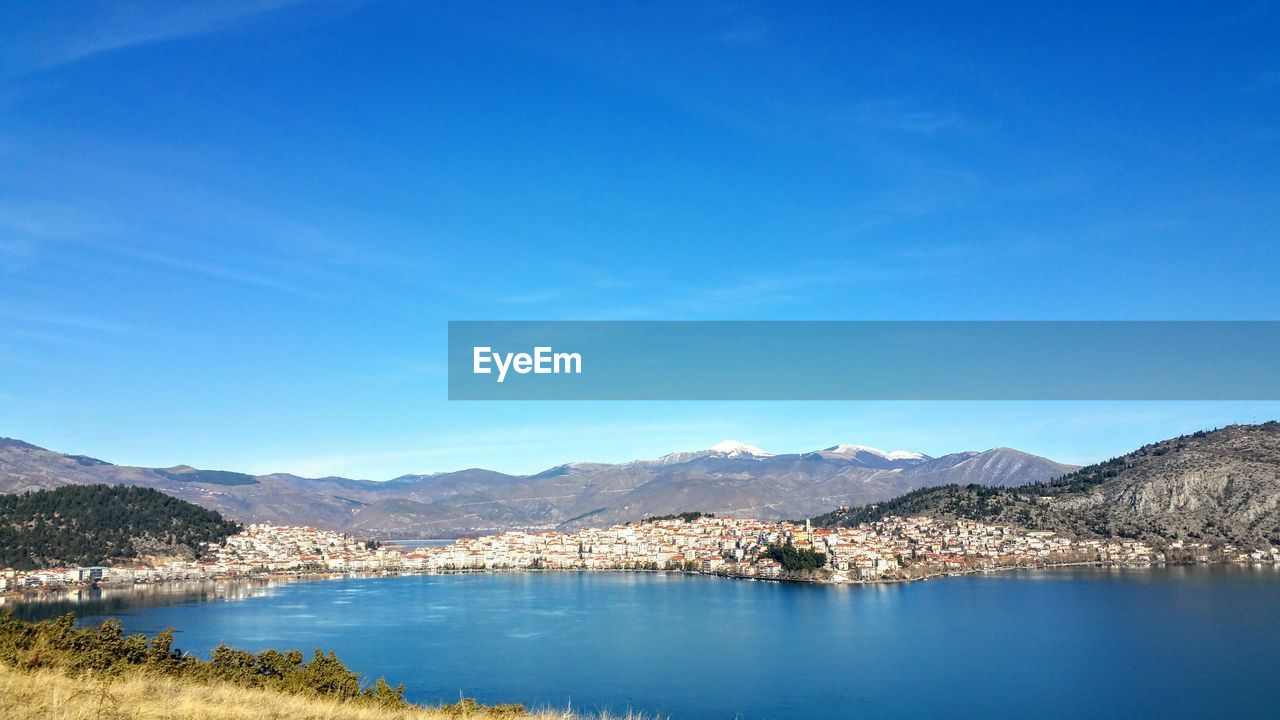 Scenic view of lake and mountains against clear blue sky