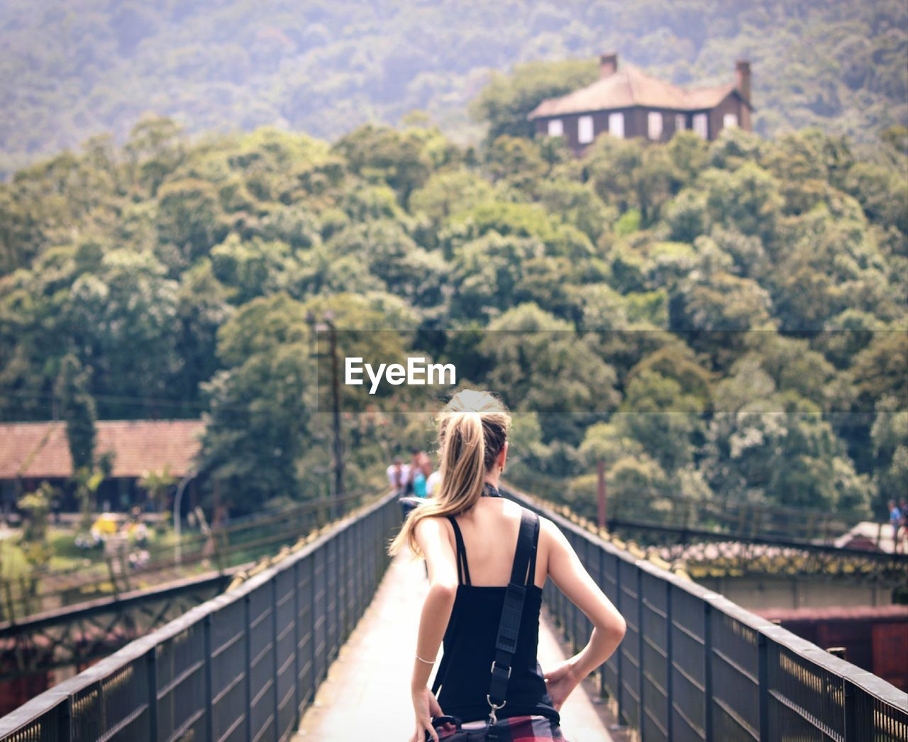 Rear view of woman on footbridge against trees