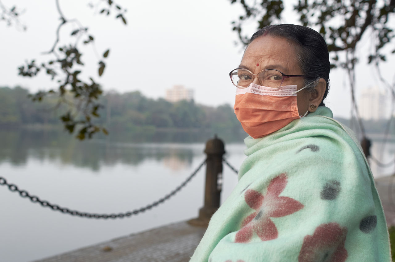 Portrait of an aged bengali woman wearing face mask during her visit at rabindra sarobar lake.