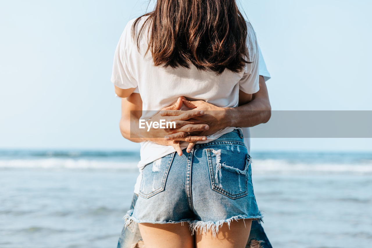 Couple embracing against sea