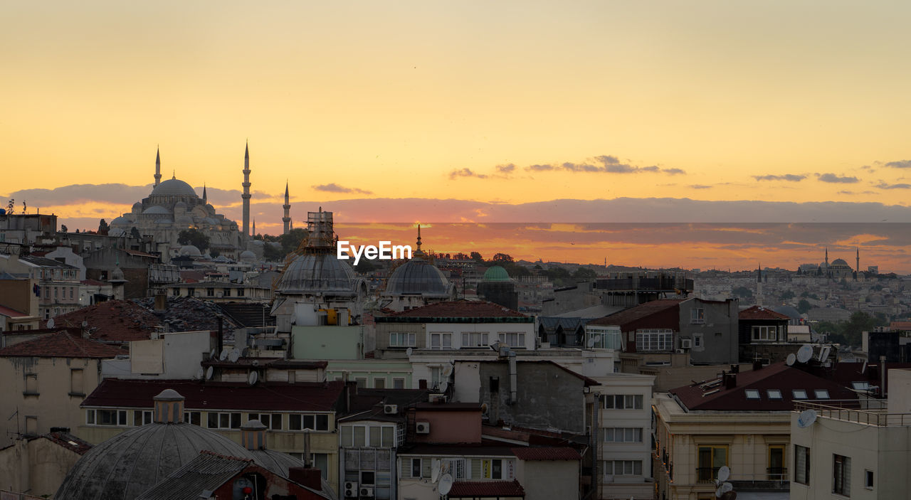 HIGH ANGLE VIEW OF BUILDINGS AGAINST SKY AT SUNSET