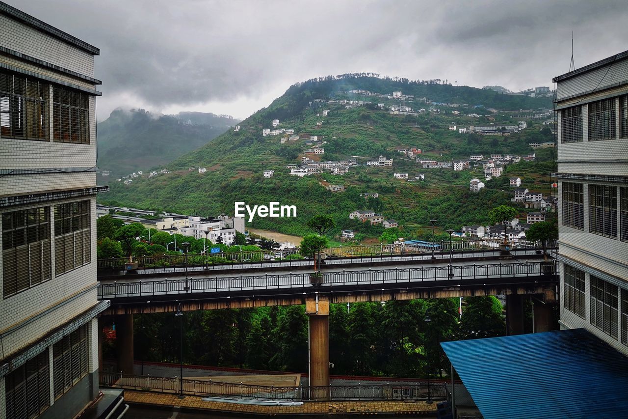 Bridge by buildings in city against sky