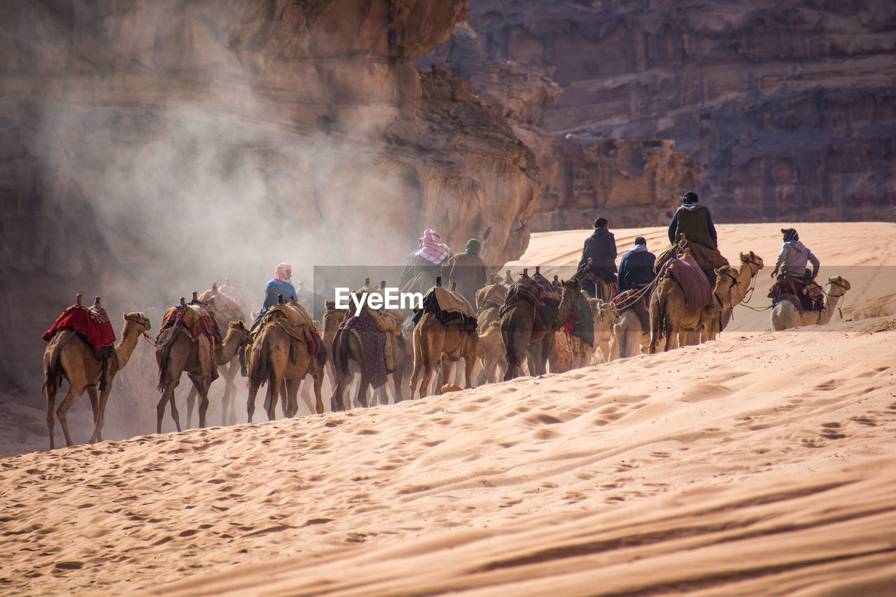 GROUP OF PEOPLE RIDING HORSE ON DESERT LAND