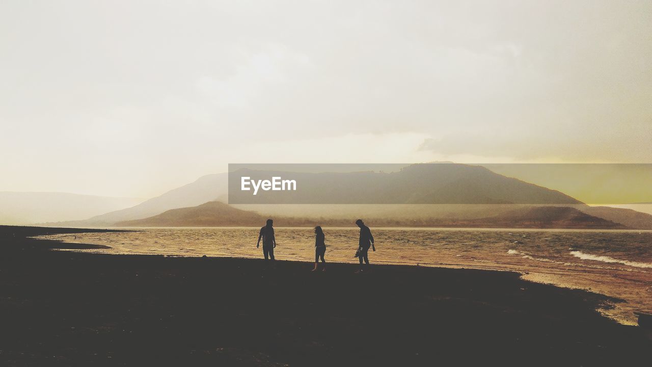 MEN ON BEACH AGAINST SKY