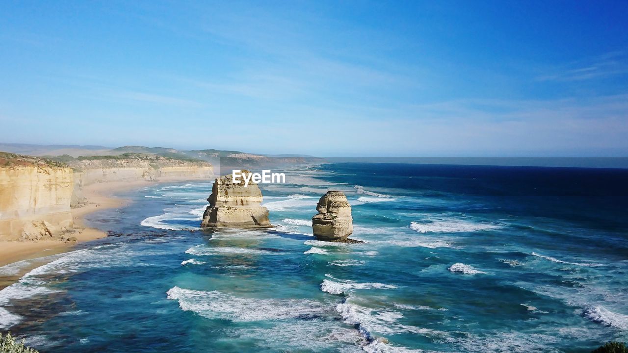 Scenic view of rocks in sea against blue sky