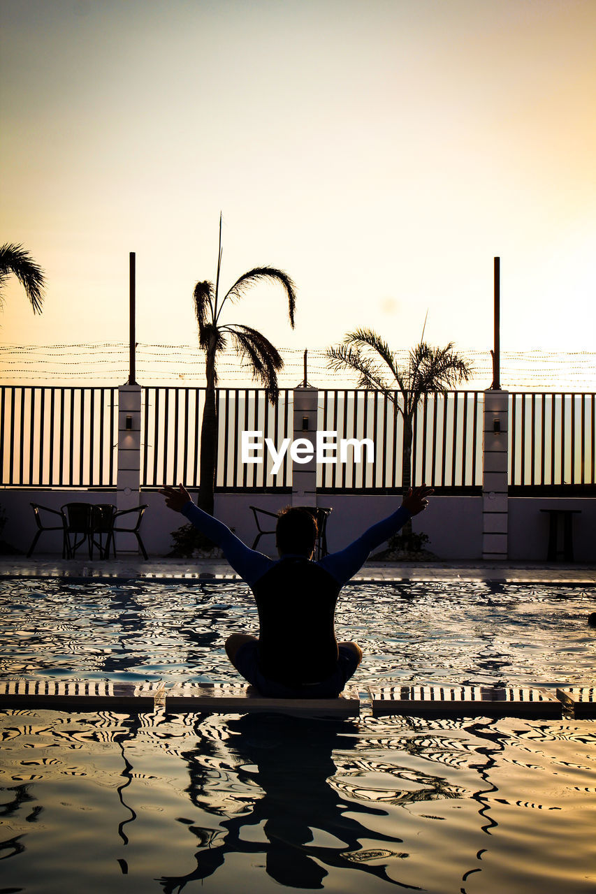 Rear view of silhouette woman by swimming pool against sky