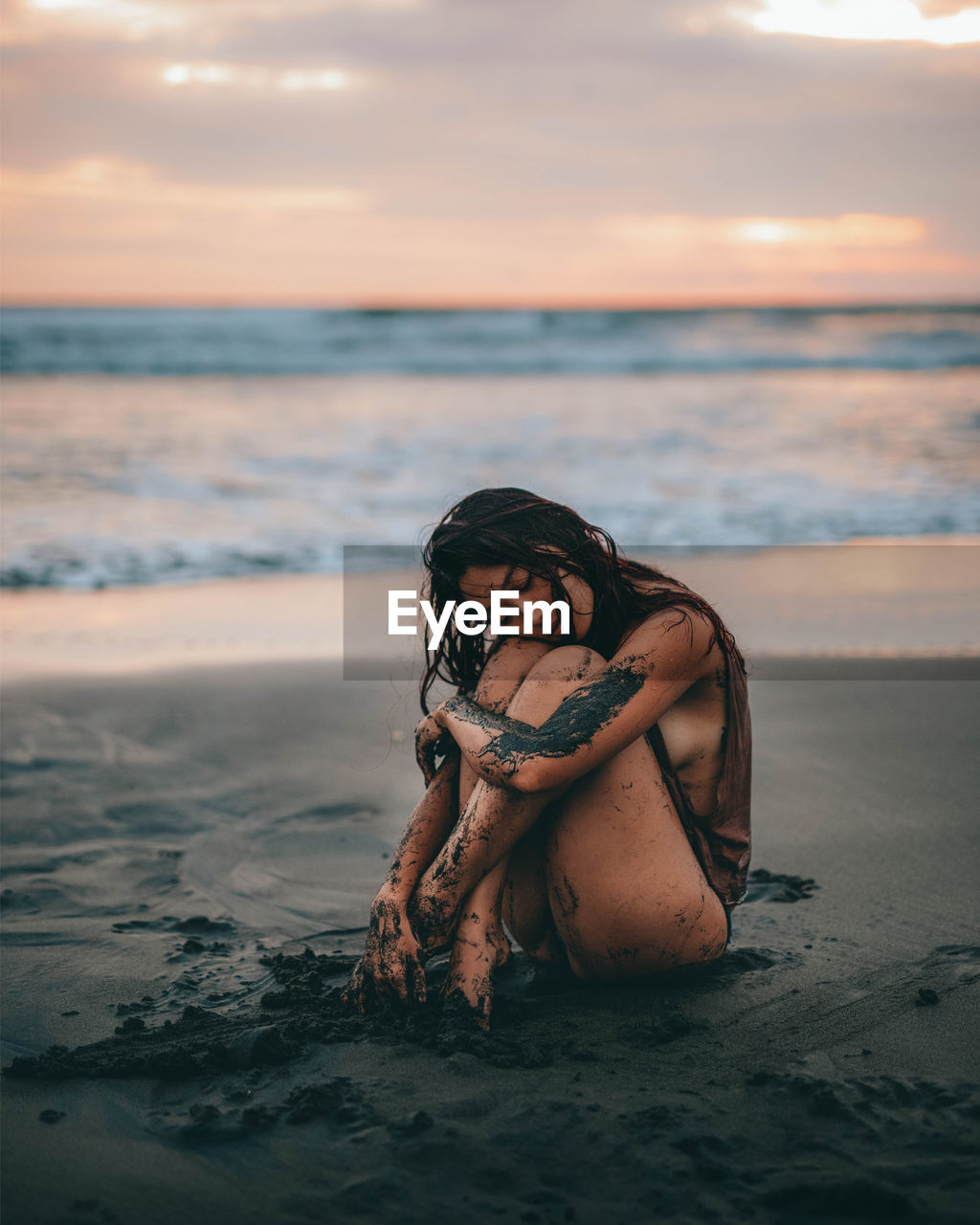 Portrait of woman at beach against sky during sunset