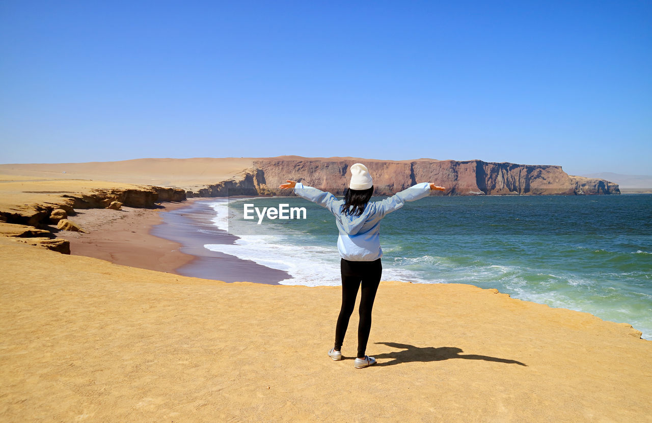 Female visitor being impressed by the red beach or playa roja of paracas national reserve, peru