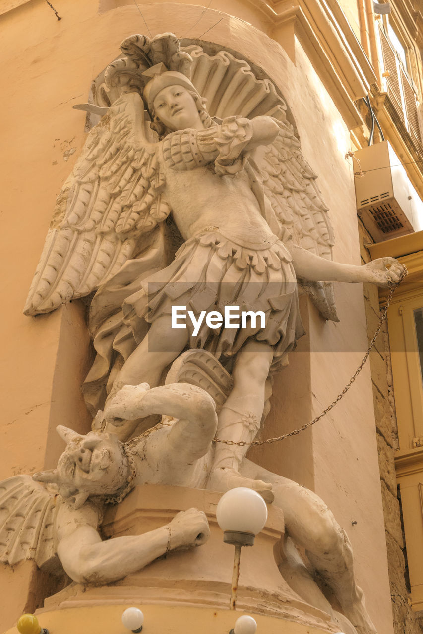 LOW ANGLE VIEW OF ANGEL STATUE AGAINST BUILDING