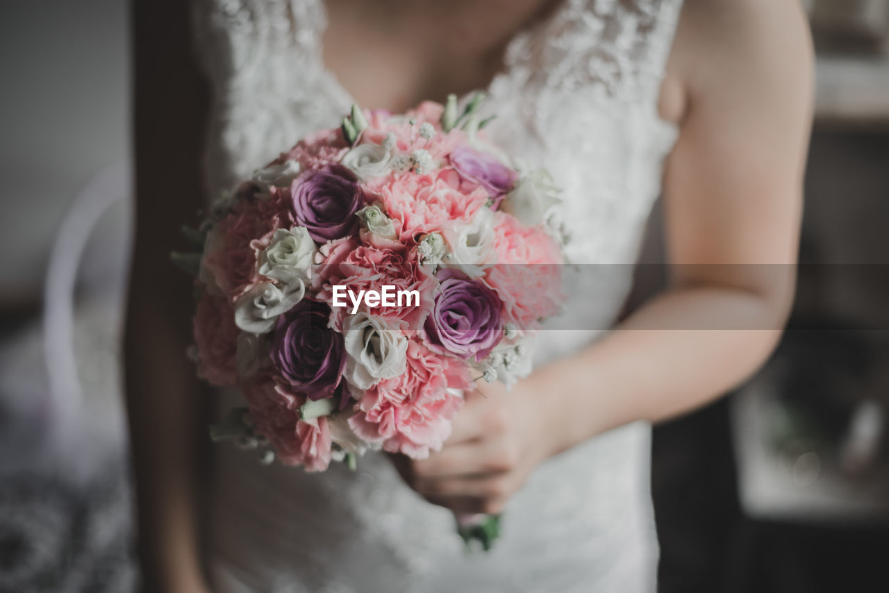 Midsection of bride holding bouquet