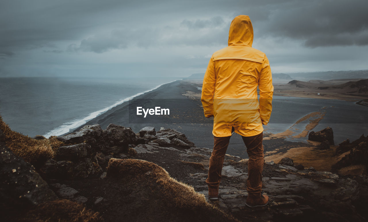 Rear view of man looking at sea against sky