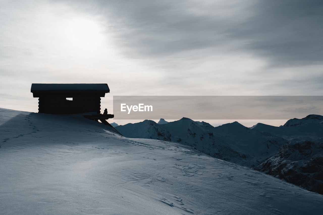 Lifeguard hut on snowcapped mountain against sky