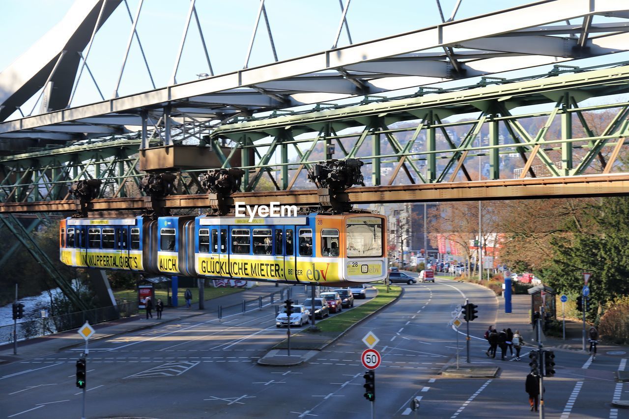 PEOPLE ON ROAD BY BRIDGE AGAINST SKY