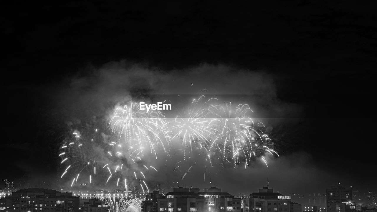 fireworks, night, firework display, celebration, illuminated, event, arts culture and entertainment, exploding, motion, black and white, architecture, firework - man made object, city, building exterior, sky, recreation, built structure, new year's eve, nature, no people, smoke, cityscape, outdoors, water, long exposure, glowing, dark