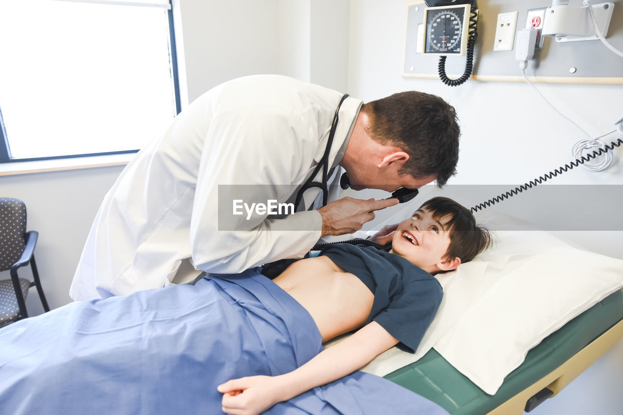Doctor looking in child's eye who is laying on exam table in clinic.
