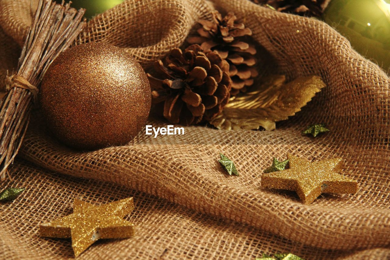 High angle view of gold baubles and pine cones on sack