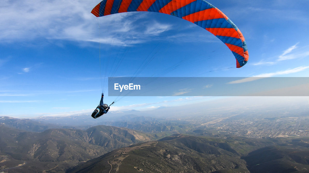AERIAL VIEW OF PERSON PARAGLIDING AGAINST SKY