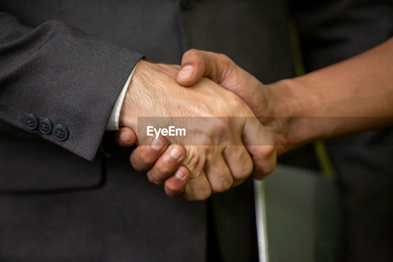Midsection of man shaking hand with colleague