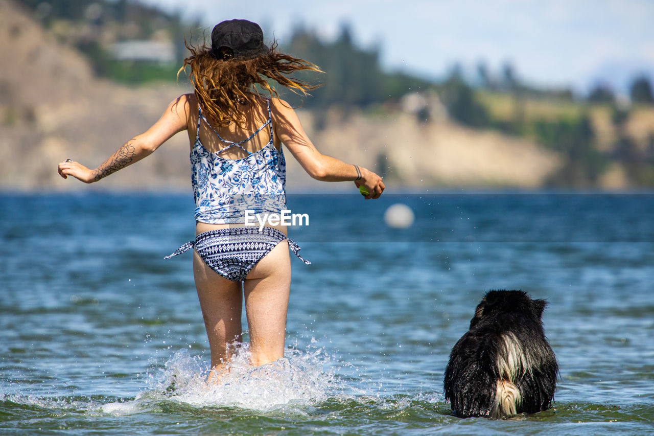 Rear view of woman with dog running in water