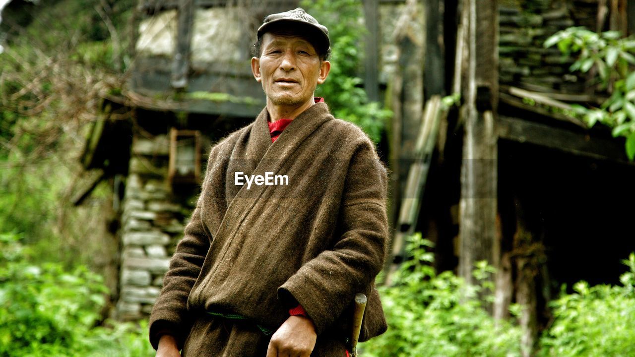 Portrait of man standing against abandoned building