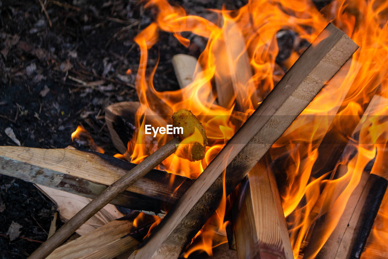 A fire burns in a campfire with a red fire in the background.